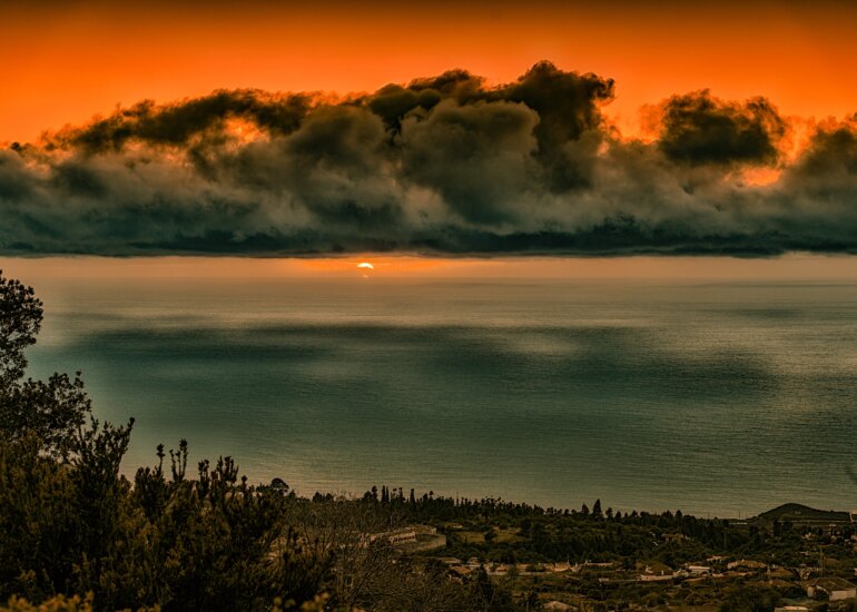 Atemberaubender Sonnenuntergang auf La Palma, mit dramatischen Wolken und einer lebhaften Spiegelung des Himmels im Wasser