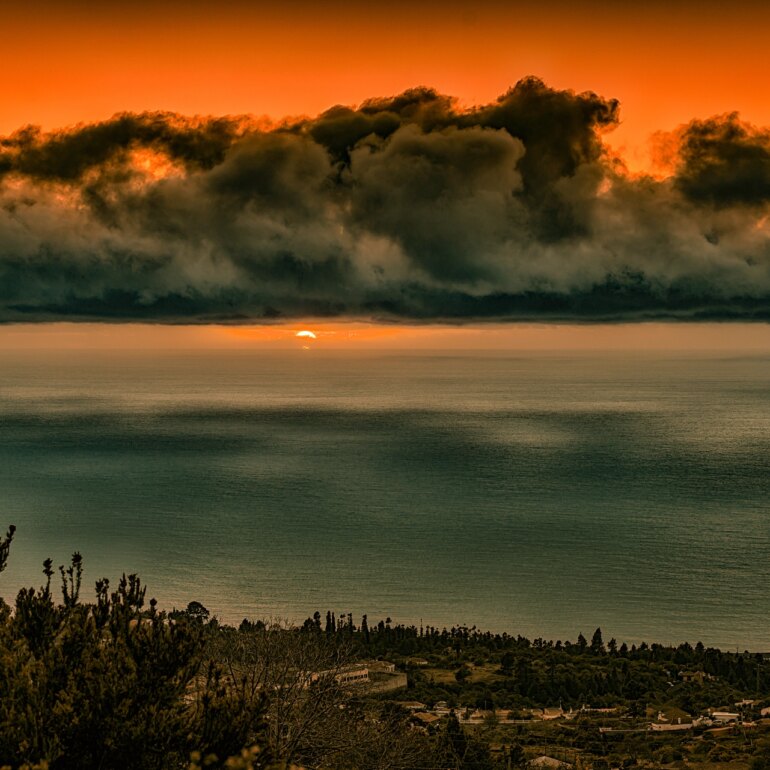 Atemberaubender Sonnenuntergang auf La Palma, mit dramatischen Wolken und einer lebhaften Spiegelung des Himmels im Wasser