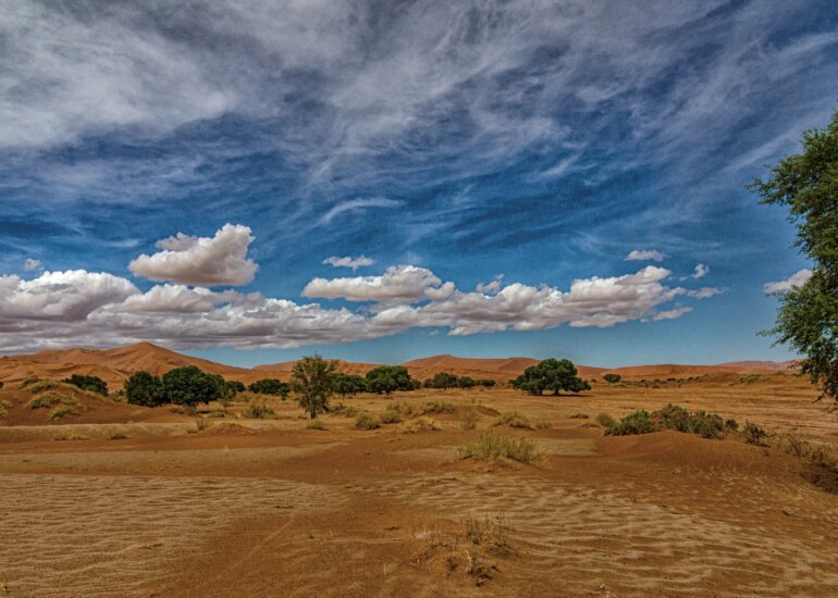 Weite Wüstenlandschaft in Namibia mit klarem Himmel und vereinzelten Wolken