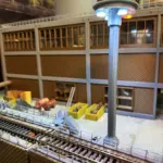 Vorplatz des Lokschuppens mit modernen LED-Laternen, Gleisanschluss und Industrieeinrichtung bei Dämmerlicht