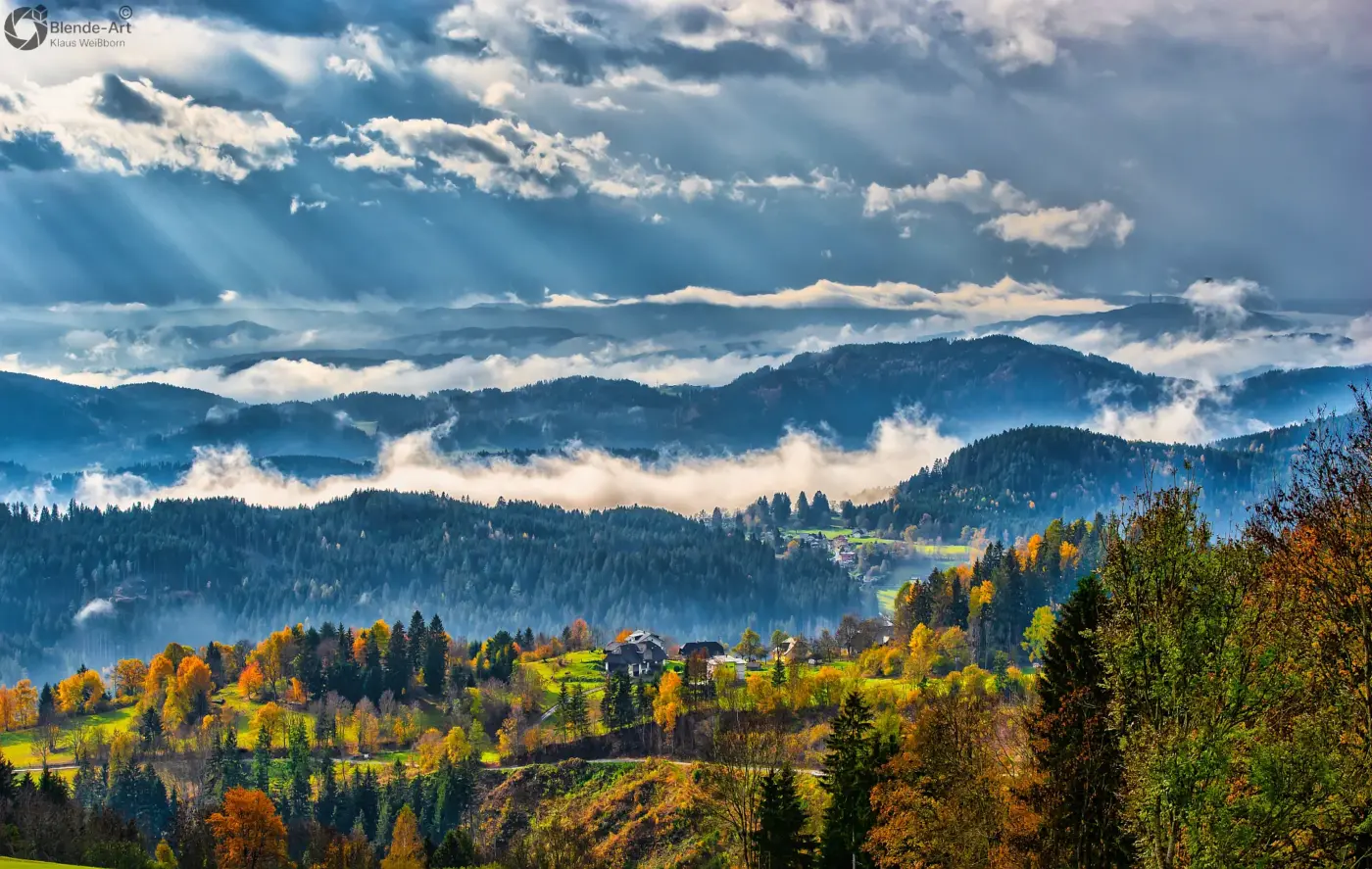 Herbstlandschaft in Kärnten, Österreich, mit farbigen Wäldern, Nebel über den Hügeln und dramatischen Wolken am Himmel