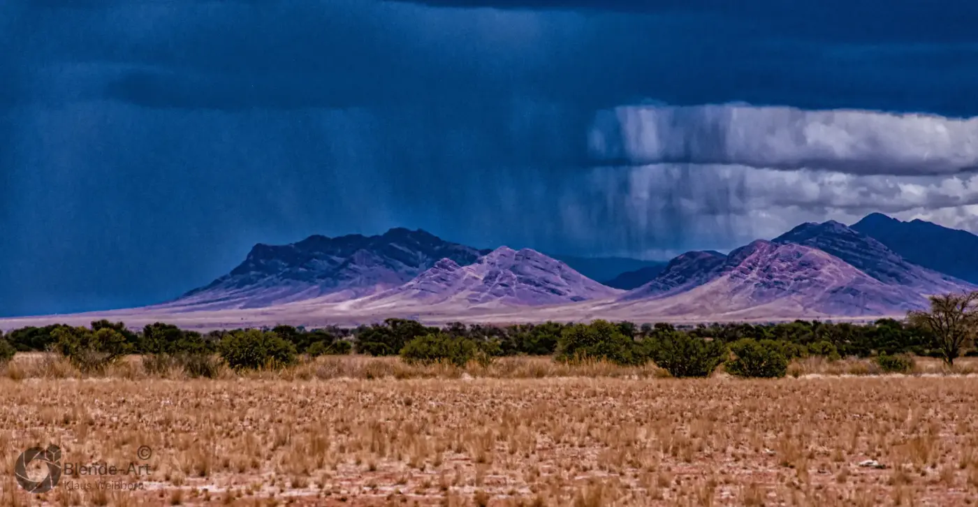Regenschauer über den Naukluft-Bergen in Namibia, mit trockener Savannenlandschaft im Vordergrund