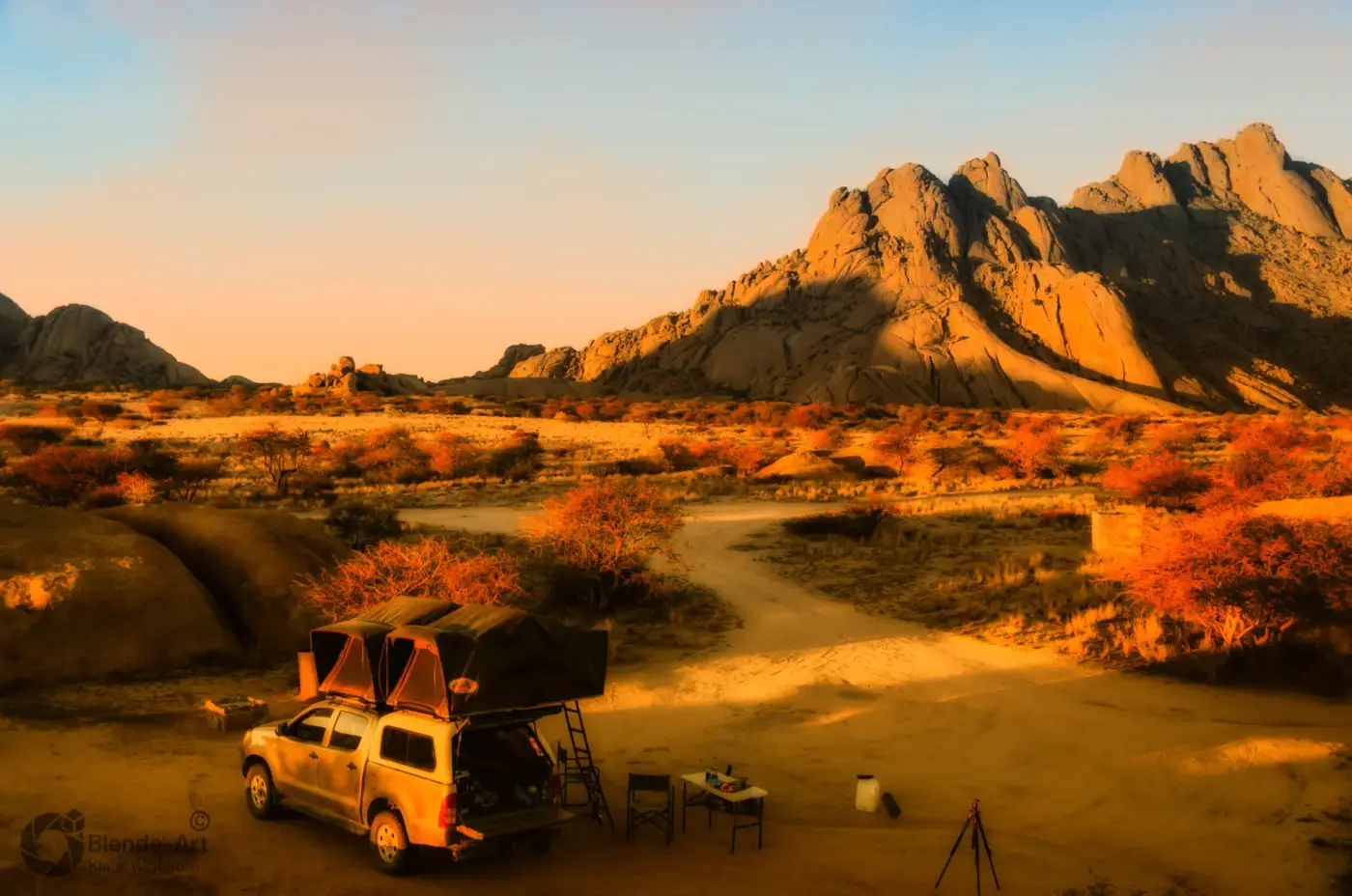 Camping mit Toyota Hilux und Dachzelt vor der imposanten Felskulisse der Spitzkoppe in Namibia bei Sonnenuntergang