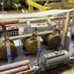 3D-Druck Tanklager mit Wellblechdach und Rohrleitungen – Modellbau Szene mit Güterwaggons