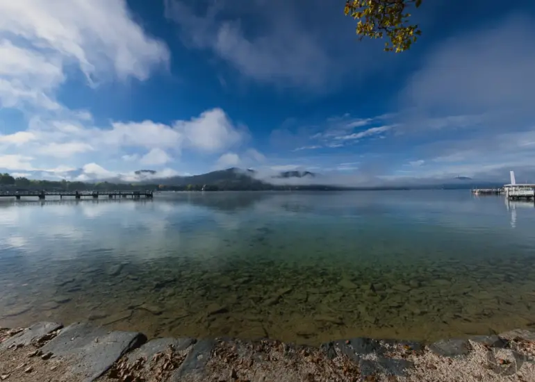 Panoramaaufnahme eines klaren Sees mit Bergen und leichtem Nebel, erstellt mit der Nikon Z7II aus fünf Einzelbildern.