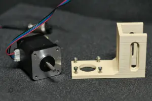 NEMA-17 Schrittmotor und 3D-gedruckte Motorhalterung mit montierten Schrauben auf dunklem Untergrund