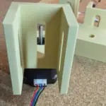 3D-gedruckte NEMA-17 Halterung mit eingesetztem Schrittmotor und Anschlusskabeln auf einer Werkbank
