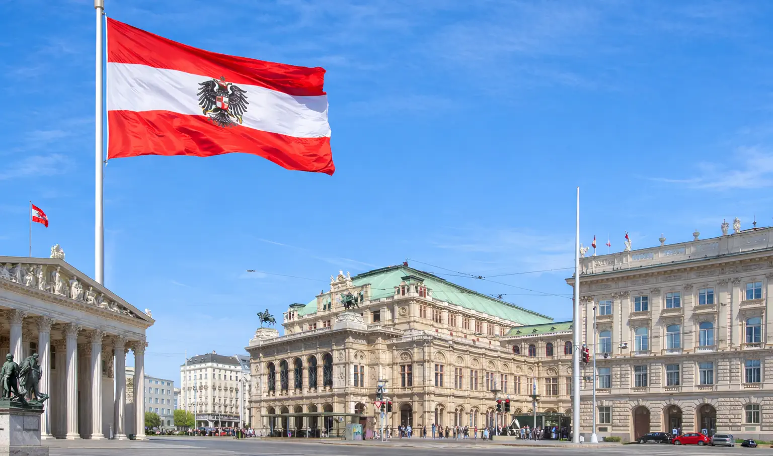 Wien Staatsoper und Parlament mit österreichischer Flagge vor blauem Himmel