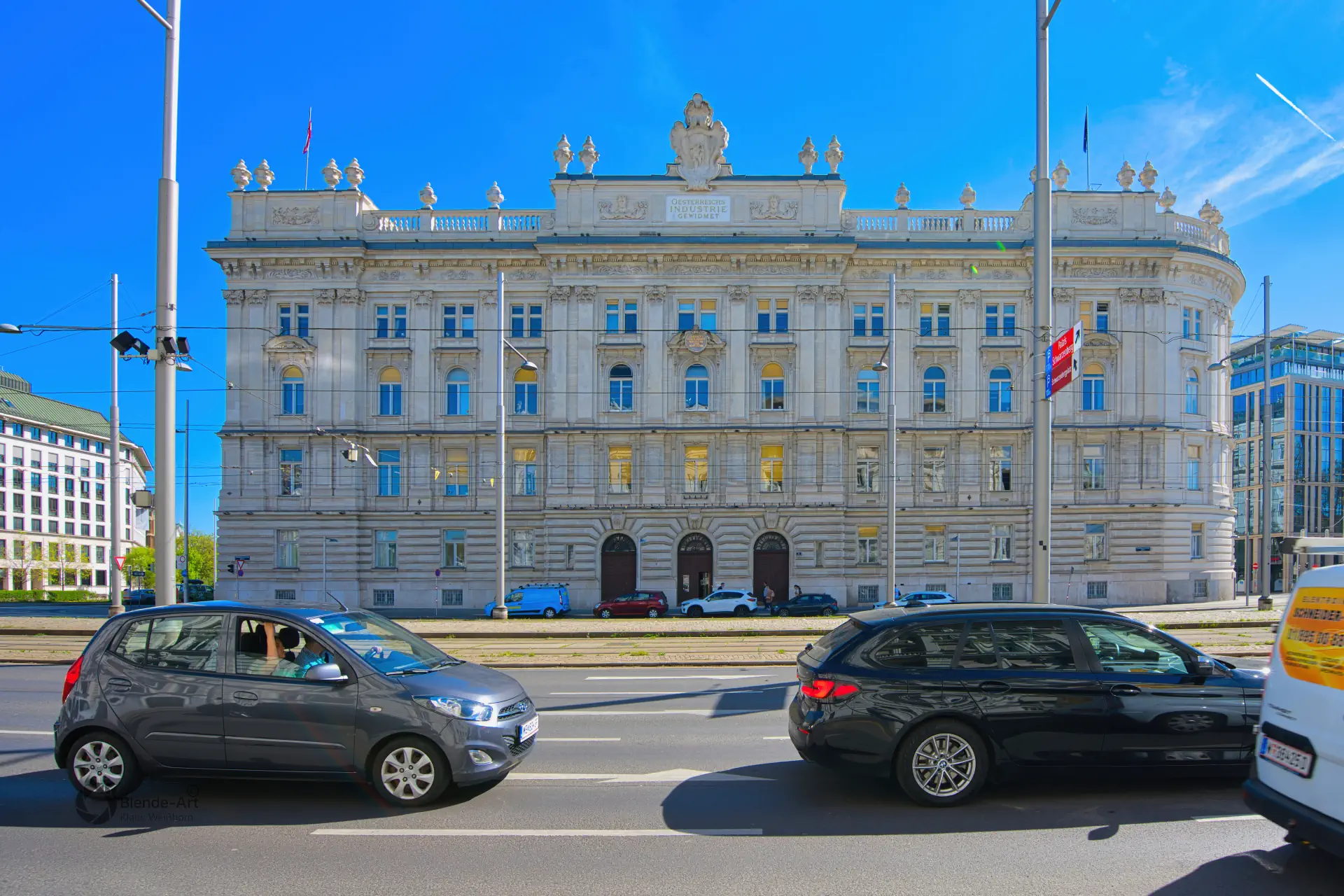Blick über den Universitätsring auf das historische Palais Ephrussi mit vorbeifahrenden Autos unter strahlend blauem Himmel.