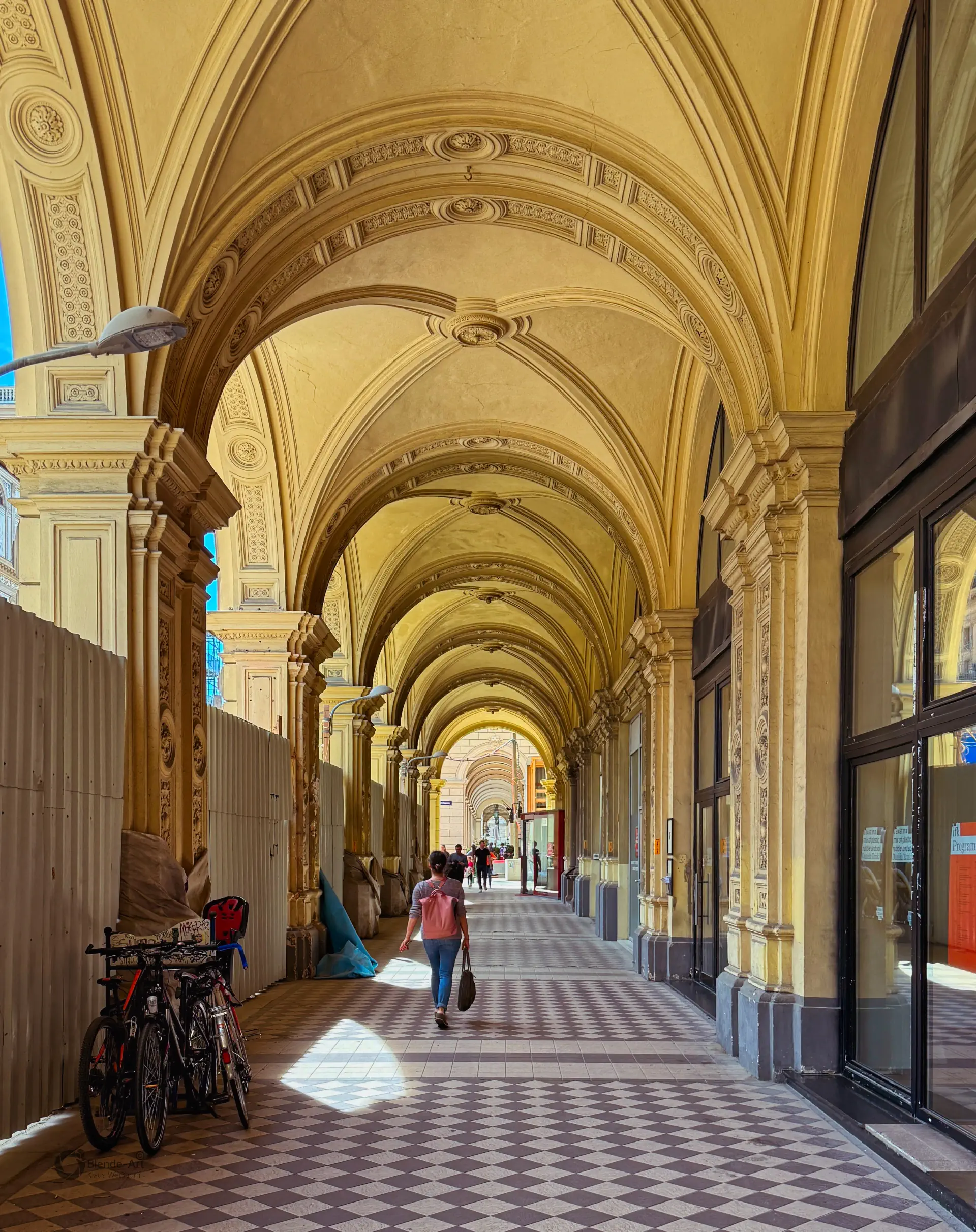 Perspektivische Ansicht eines prachtvollen Arkadengangs im Wiener Palais Ferstel mit eleganten Rundbögen und historischer Architektur.