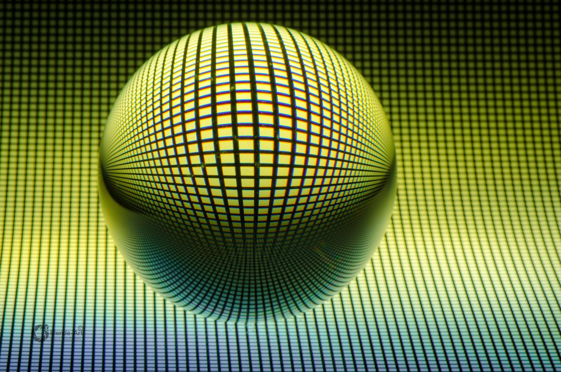 Glaskugel mit gelb-grünem Rastermuster auf dunklem Hintergrund, das durch Lichtbrechung kugelförmig verzerrt wird