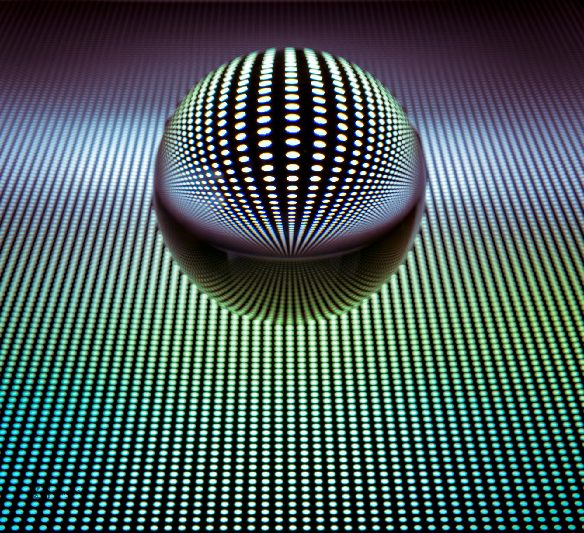 Glaskugel mit farbigem Punktmuster auf Verlaufshintergrund von Grün zu Violett, das durch Lichtbrechung perspektivisch verzerrt wird