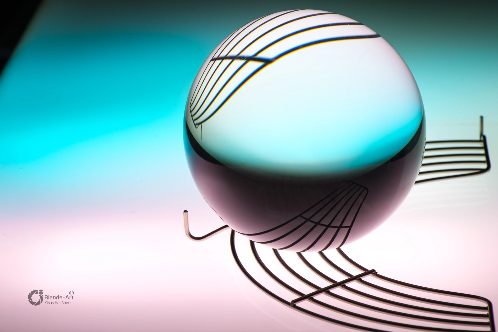 Glaskugel auf türkisfarbenem Hintergrund mit feinen Linien, die durch Lichtbrechung um die Kugel gebogen und verzerrt erscheinen