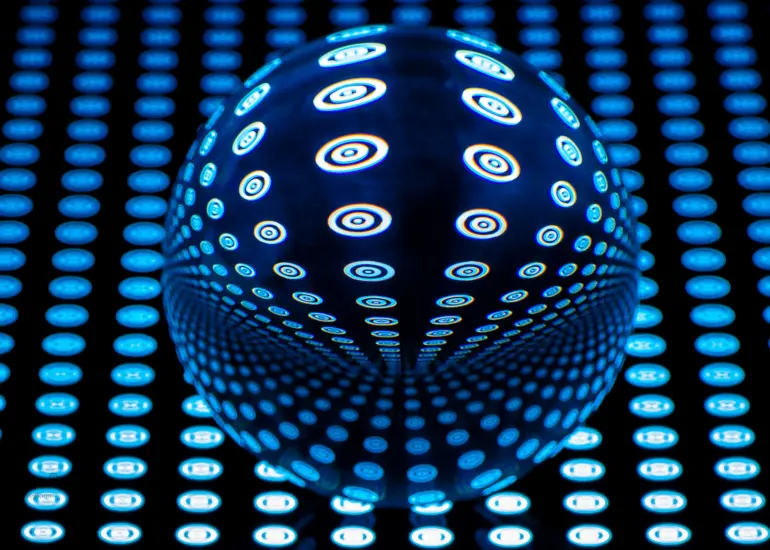 Glaskugel mit blauem Punktmuster auf dunklem Rasterhintergrund, das durch Lichtbrechung symmetrisch verzerrt wird