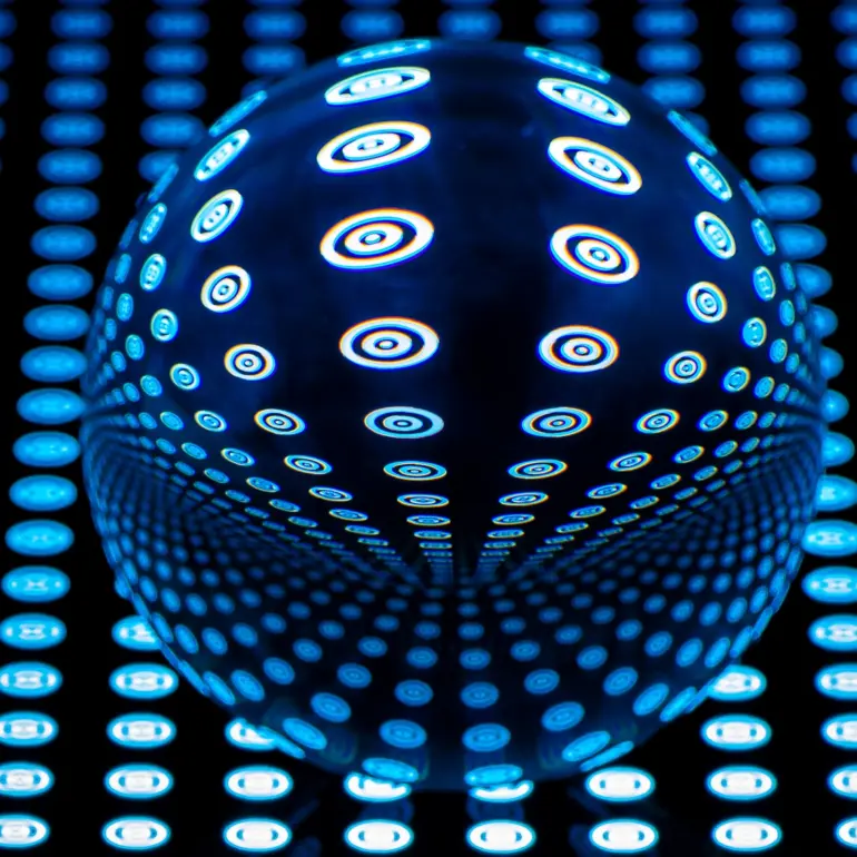 Glaskugel mit blauem Punktmuster auf dunklem Rasterhintergrund, das durch Lichtbrechung symmetrisch verzerrt wird