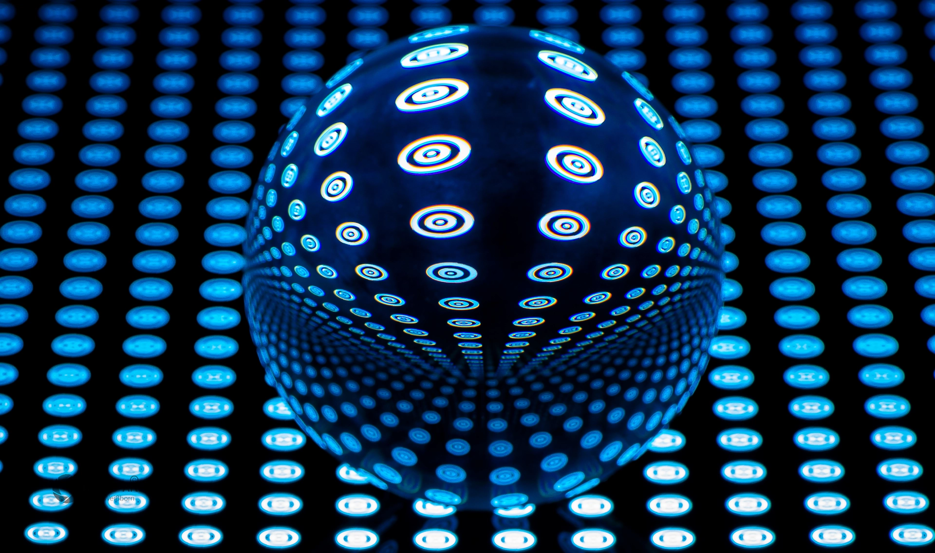 Glaskugel mit blauem Punktmuster auf dunklem Rasterhintergrund, das durch Lichtbrechung symmetrisch verzerrt wird