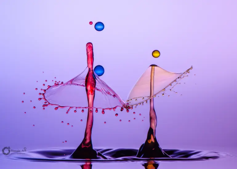 Zwei gegenüberstehende Tropfensäulen mit ausgebreiteten Flüssigkeitsformen und mehreren schwebenden Kugeltropfen