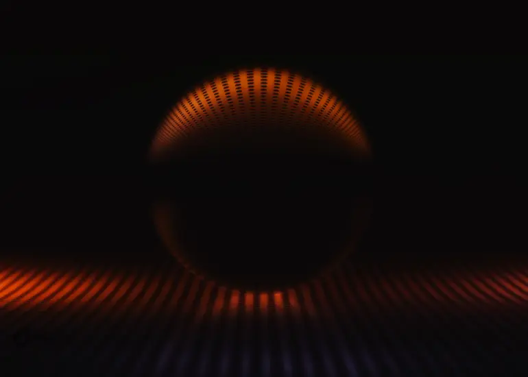 Glaskugel Fotografie mit orangen Lichtraster und dunklem Lichtakzent auf schwarzem Hintergrund