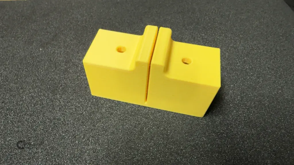 Gelbe 3D-gedruckte Sägehilfe für 30 × 30-mm-Aluminiumprofile mit mittigem Sägeschlitz und Befestigungsbohrungen