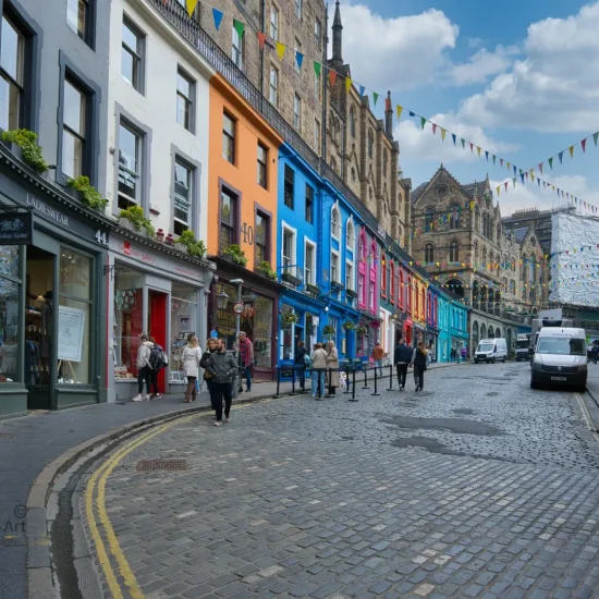 Farbenfrohe Fassaden der Victoria Street in Edinburgh mit Kopfsteinpflaster und Menschen bei sonnigem Wetter.