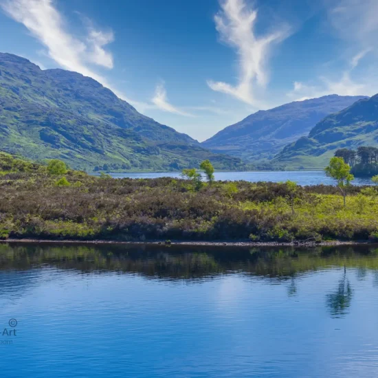 Blick über Loch Shiel in den schottischen Highlands bei blauem Himmel, mit Bergen und Spiegelungen im Wasser.