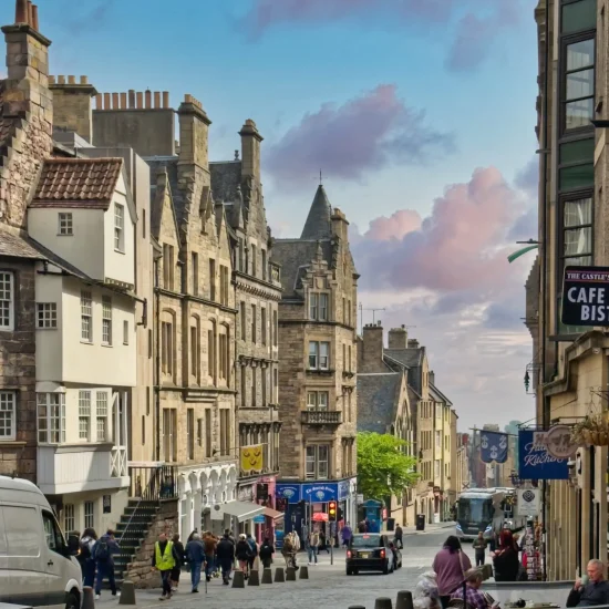 Menschen auf der Royal Mile in Edinburgh bei sonnigem Wetter, umgeben von historischen Gebäuden.